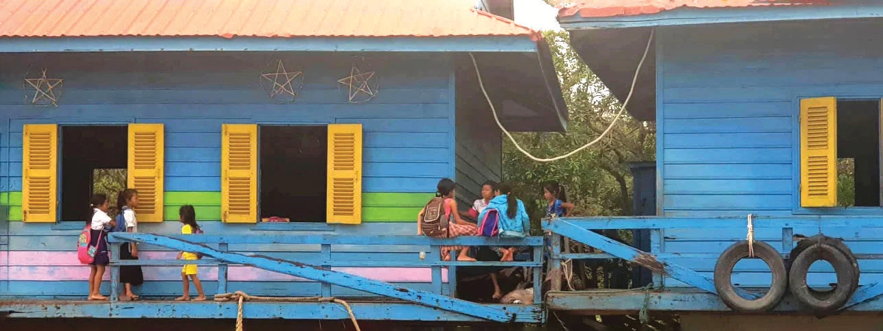 Các em học sinh đang tập trung trước một ngôi trường nổi màu xanh trên Biển Hồ (Tonlé Sap) ở Campuchia.